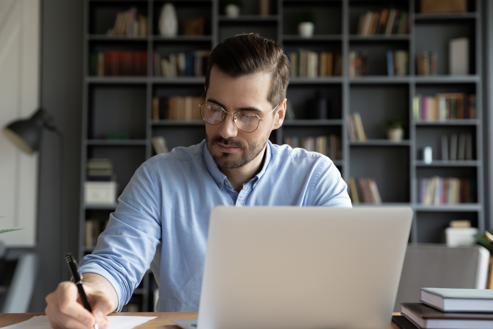 Man working alongside laptop in study medium