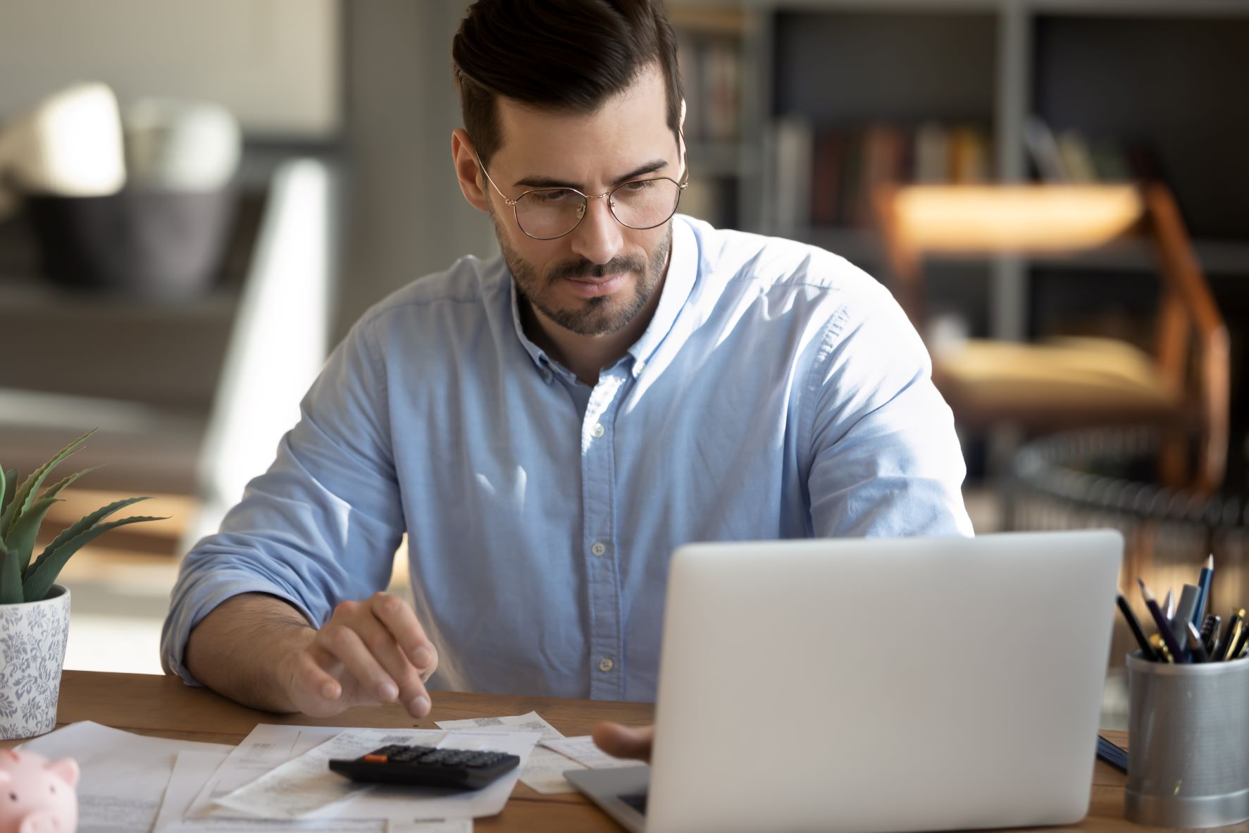 man sat at desk laptop calculator